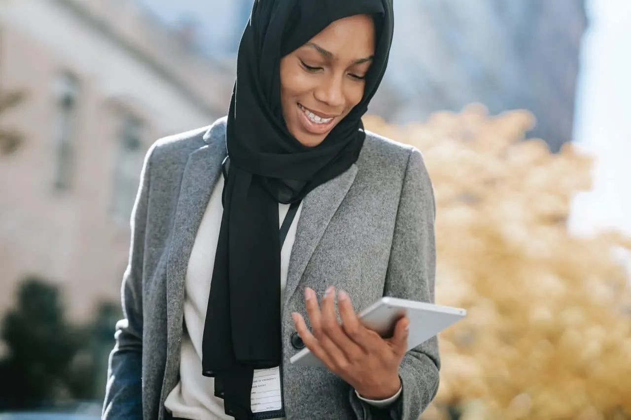 black woman in hijab browsing tablet